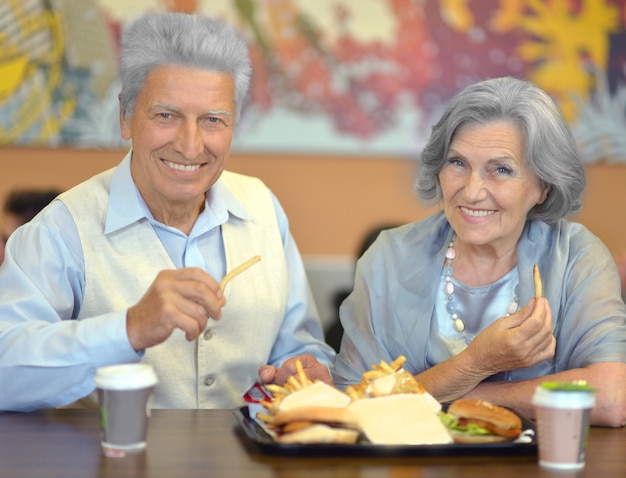 Portret van mooi bejaarde echtpaar dat fastfood eet