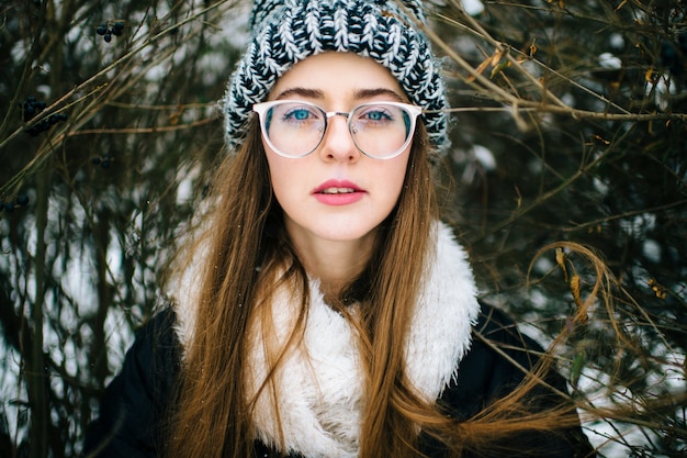 Portret van mooi en stijlvol donkerbruin meisje in glazen in de winterpark.