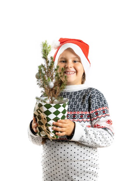 Portret van mooi gelukkig meisje in witte kersttrui met rendieren en kerstman hoed vasthouden...