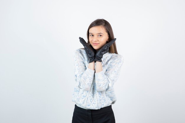 Portret van mooi jong meisje in zwarte handschoenen die voor camera stellen.