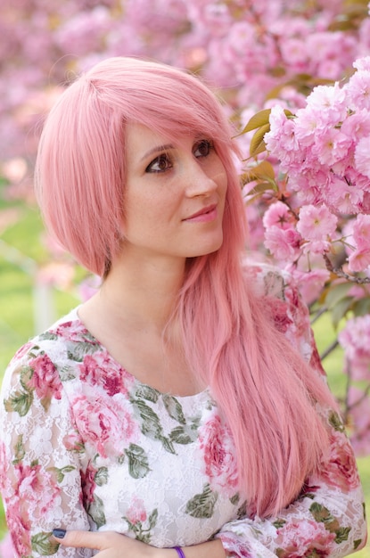 Portret van mooi meisje in sakuraboom. Sakura-bloemen omringen het meisje. Sakura-tak aan haar gezicht