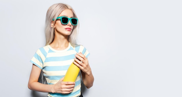 Portret van mooi meisje met gele thermo waterfles op witte achtergrond met kopie ruimte