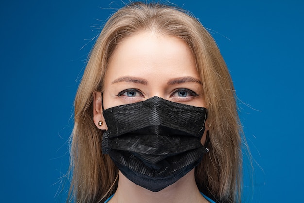 Portret van mooi meisje met lang blond haar met medische masker op haar gezicht