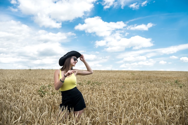 Portret van mooi meisje poseren in tarweveld genieten van zomertijd. vrijheid