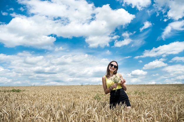 Portret van mooi meisje poseren in tarweveld genieten van zomertijd. vrijheid