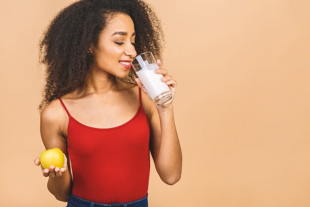 Portret van mooie afrikaanse amerikaanse vrouw met glas melk en appel