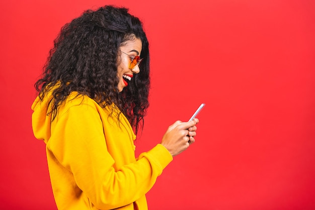 Portret van mooie Afrikaanse Amerikaanse vrouw met zonnebril die telefoon met behulp van