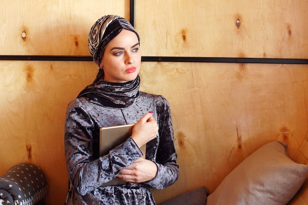 Foto portret van mooie arabische moslim meisje zit in café met tablet