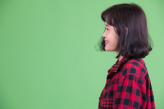 Portret van mooie Aziatische hipster vrouw met kort haar tegen Chromakey of groene muur