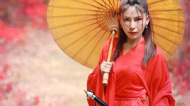 Portret van mooie aziatische vrouw die een rood krijger Chinees kostuum draagt \