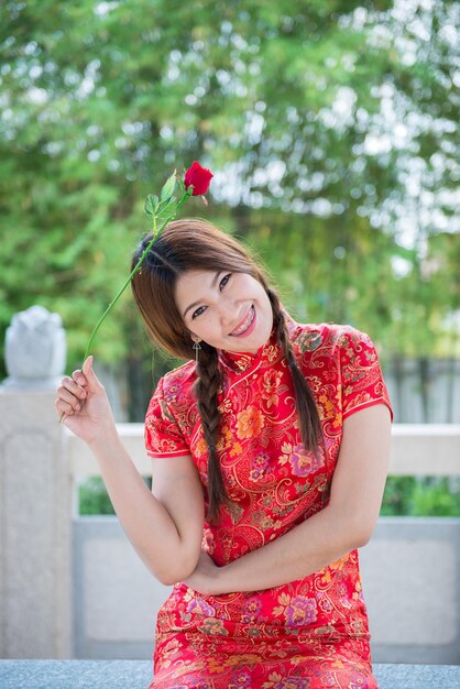 Portret van mooie Aziatische vrouw in Cheongsam-jurk met Red Rose in de hand Thailand-mensen Gelukkig Chinees nieuwjaarsconcept