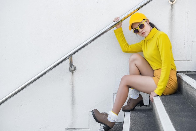 Portret van mooie aziatische vrouw in gele doeken hipsters meisje draagt een gele hoed op de trap om een foto te maken thailand-mensen in gele toonstijl
