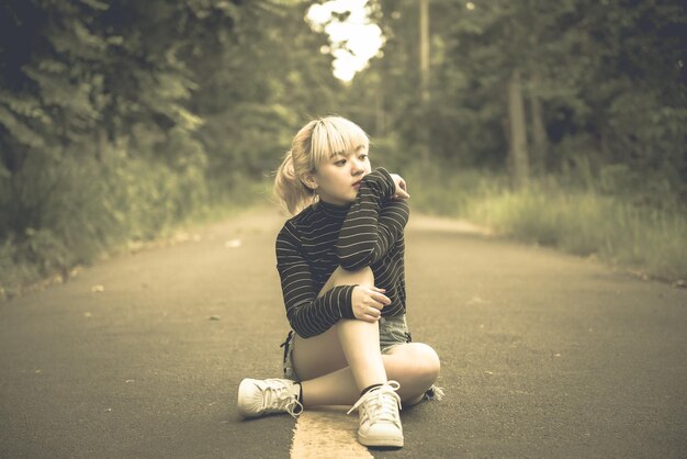 Portret van mooie aziatische vrouw op de weg bij bos vintage stijldonker tonethailand meisje gouden haren