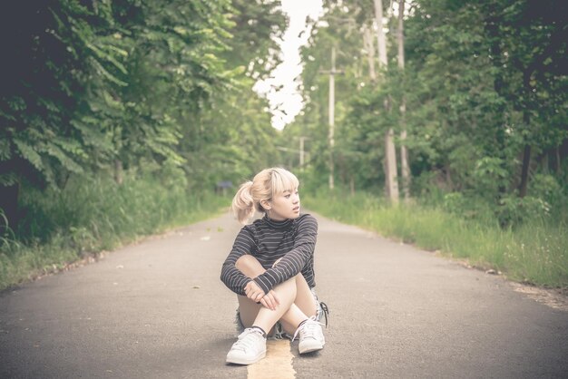 Portret van mooie aziatische vrouw op de weg bij bos vintage stijldonker tonethailand meisje gouden haren