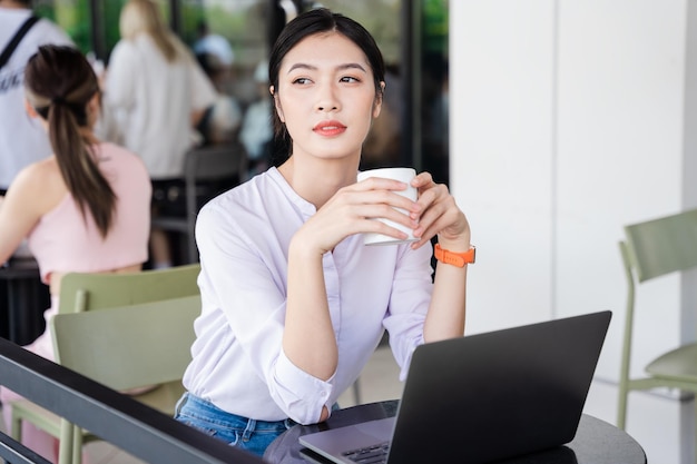 Portret van mooie aziatische vrouwenzitting bij koffie
