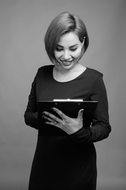 Portret van mooie Aziatische zakenvrouw op grijs in zwart-wit