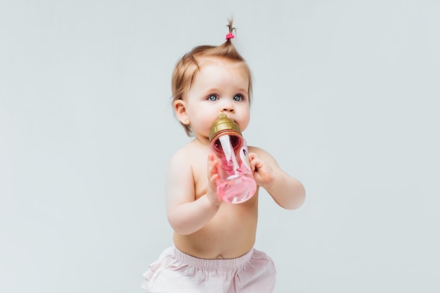 Portret van mooie baby meisje peuter verblijf in luier met roze fles water