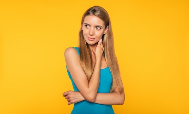 Portret van mooie blonde jonge vrouw in casual kleding. Zelfverzekerd schattig meisje poseert over gele muur. Stijl en mode. Schoonheid en gezondheidszorg. Vrouwen leven