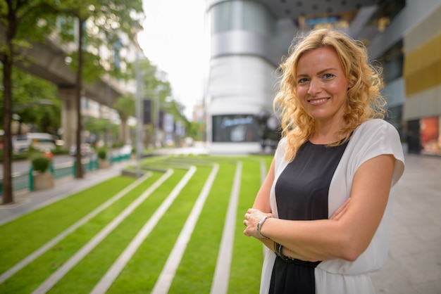 Portret van mooie blondeonderneemster die in openlucht glimlacht