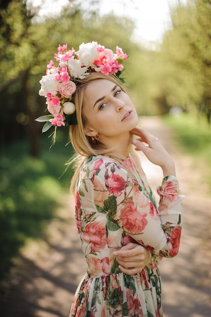 Portret van mooie blondevrouw gekleed in bloemkleding en roze kroon
