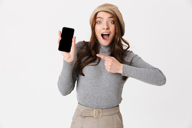 Portret van mooie gelukkige vrouw geïsoleerd op een witte muur met weergave van mobiele telefoon.