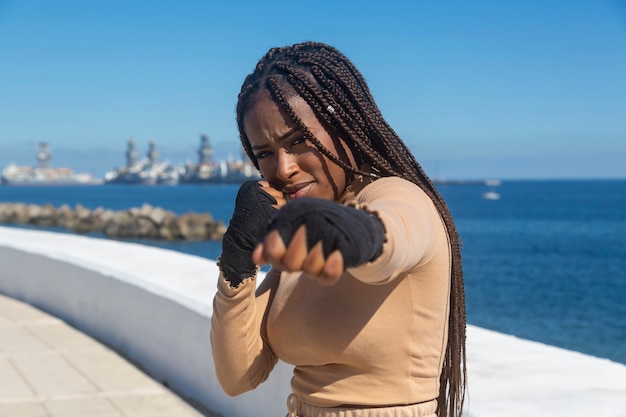 Portret van mooie jonge afro amerikaanse vrouw, met pleisters op haar handen om vechtsporten te beoefenen, boksen.