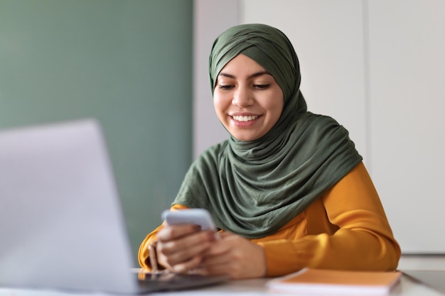 Portret Van Mooie Jonge Arabische Vrouw In Hijab Met Smartphone In Office