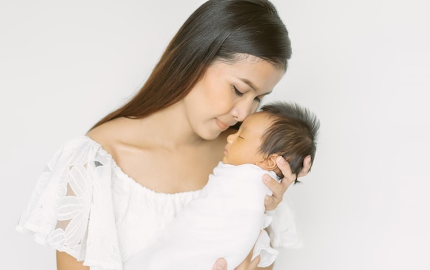 Portret van mooie jonge Aziatische moeder zoenen pasgeboren zoon op witte achtergrond Geniet van tedere familie