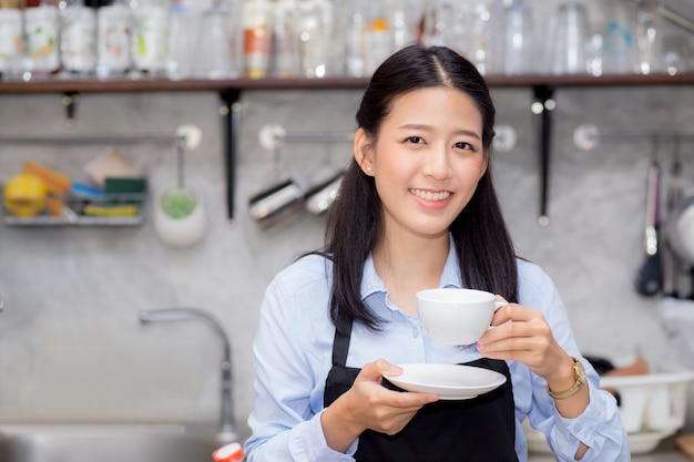 Portret van mooie jonge barista die een kop van koffie drinkt.