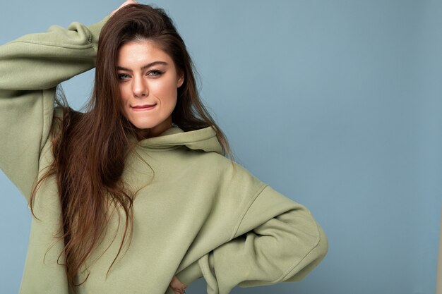 Portret van mooie jonge blanke lachende brunette vrouw model in trendy kaki hoodie geïsoleerd