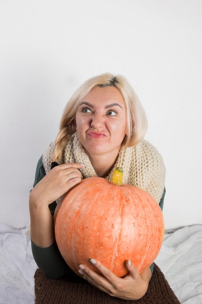 Portret van mooie jonge blonde vrouw met pompoen klaar voor halloween-vieringsmodel voor ansichtkaart en uitnodiging of advertentie