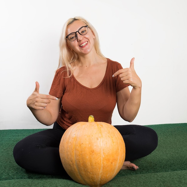 Portret van mooie jonge blonde vrouw met pompoen klaar voor halloween-vieringsmodel voor ansichtkaart en uitnodiging of advertentie