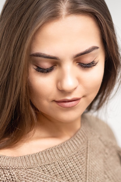 Portret van mooie jonge Kaukasische vrouw met gesloten ogen na de procedure van de wimperextensie en permanente make-up