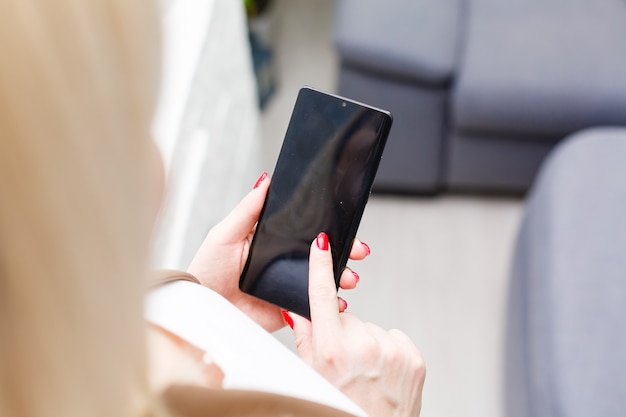 Portret van mooie jonge vrouw die haar mobiele telefoon thuis met behulp van.