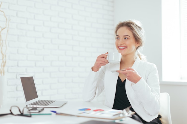 Portret van mooie jonge vrouw die in het bureau werkt.