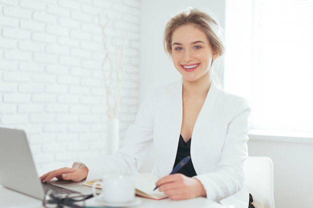 Portret van mooie jonge vrouw die werkt in het kantoor.