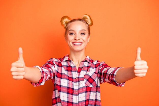 Foto portret van mooie jonge vrouw gekleed in een geruite geruit overhemd geïsoleerd op oranje