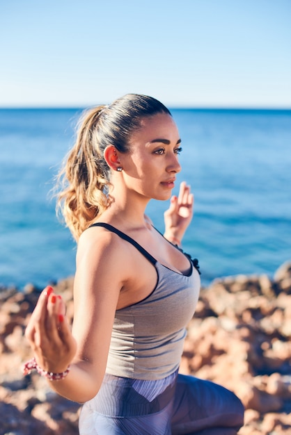 Portret van mooie jonge vrouw het beoefenen van yoga op zee tegen blauwe zee.