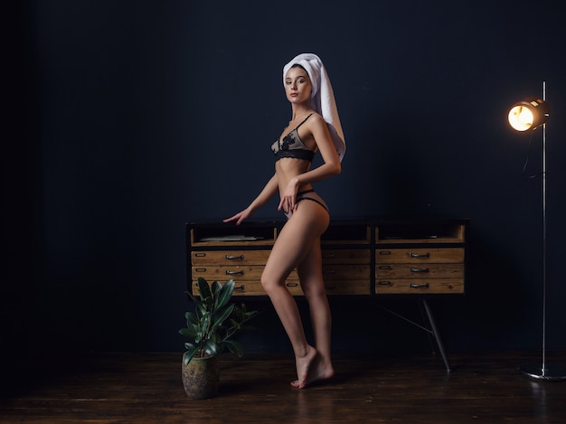 Portret van mooie jonge vrouw in lingerie zittend in stoel met handdoek op hoofd en boek in handen