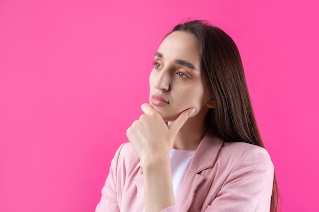 Portret van mooie jonge vrouw in roze jas denken geïsoleerd op rode achtergrond