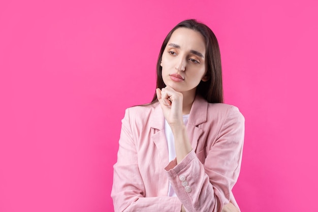 Portret van mooie jonge vrouw in roze jas denken geïsoleerd op rode achtergrond