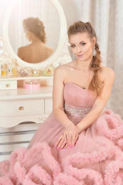 Portret van mooie jonge vrouw in roze jurk poseren