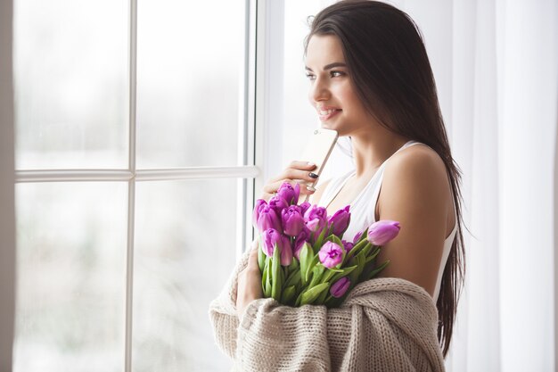 Portret van mooie jonge vrouw met bloemen. Aantrekkelijk meisje bedrijf tulpen