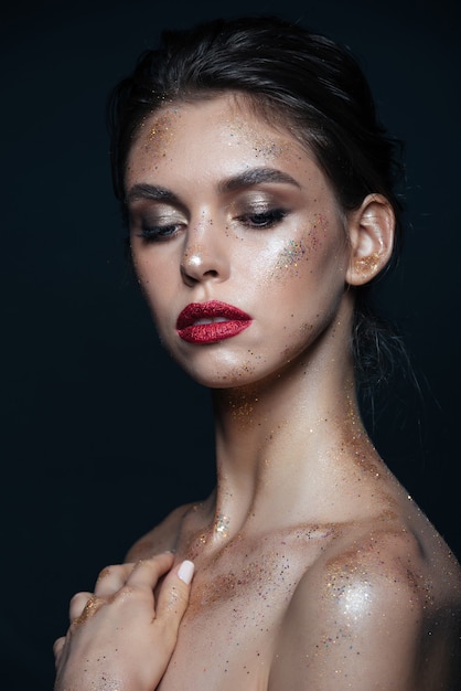 Portret van mooie jonge vrouw met heldere glanzende make-up over zwart oppervlak