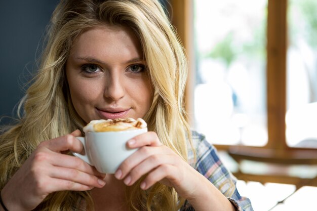 Portret van mooie jonge vrouw met koffie in café