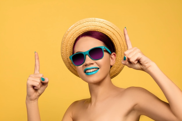 Portret van mooie jonge vrouw met lichte make-up geïsoleerd op gele studio background