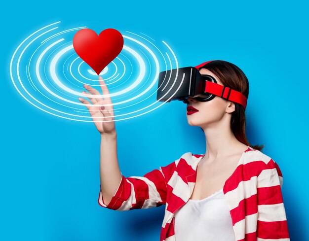 Portret van mooie jonge vrouw met virtual reality-gadget op blauwe ruimte