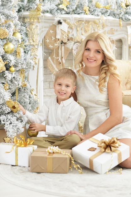 Portret van mooie jonge vrouw met zoon poseren in kamer versierd met kerstvakantie