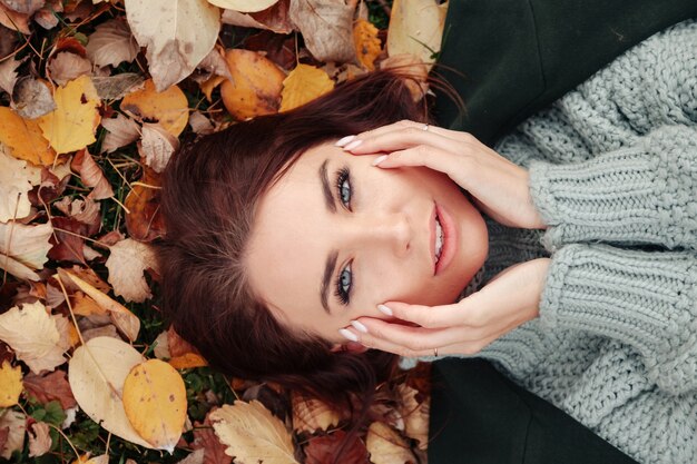 Portret van mooie jonge vrouw van slavische verschijning in casual kleding in de herfst, liggend op gele herfstbladeren. schattig model loopt in park in gouden herfst tegen de achtergrond van de natuur. ruimte kopiëren