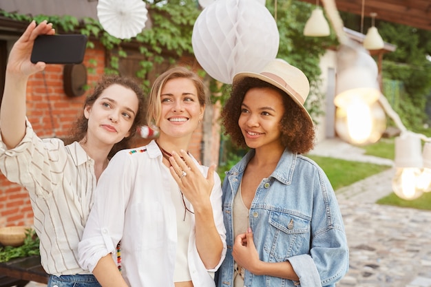 Portret van mooie jonge vrouw weergegeven: verlovingsring selfie met vrienden nemen tijdens buitenfeest